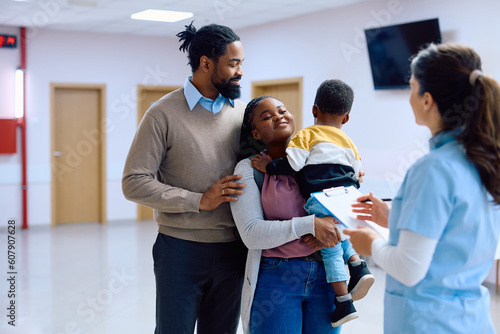 Happy black family talking to nurse in hallway at medical clinic.