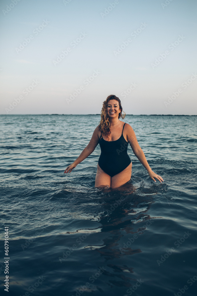 woman standing in the ocean splashing water at the beach