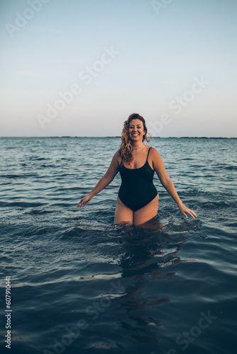 woman standing in the ocean splashing water at the beach