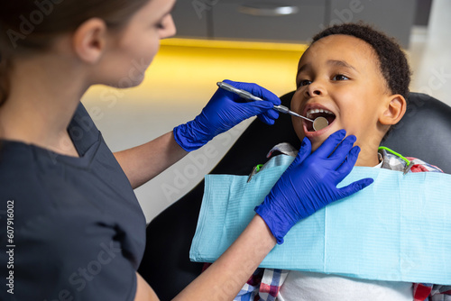 Female doctor checking up dark-skinned boy