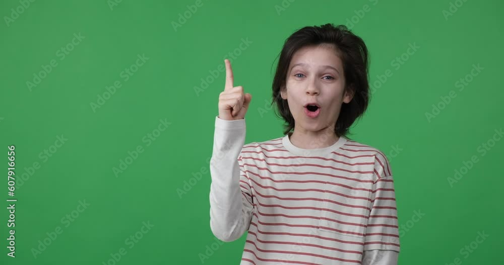 A young schoolboy stands on a green screen and looks pensive, hand on his chin. Suddenly, an idea strikes him, and he looks up with a wide grin, raising his finger in excitement. A young schoolboy stands on a green screen and looks pensive, hand on his chin. Suddenly, an idea strikes him, and he looks up with a wide grin, raising his finger in excitement.