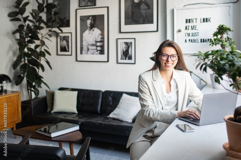 Happy businesswoman using laptop working online and smiling to camera, sitting in coworking space interior, free space Happy businesswoman using laptop working online and smiling to camera, sitting in coworking space interior, free space
