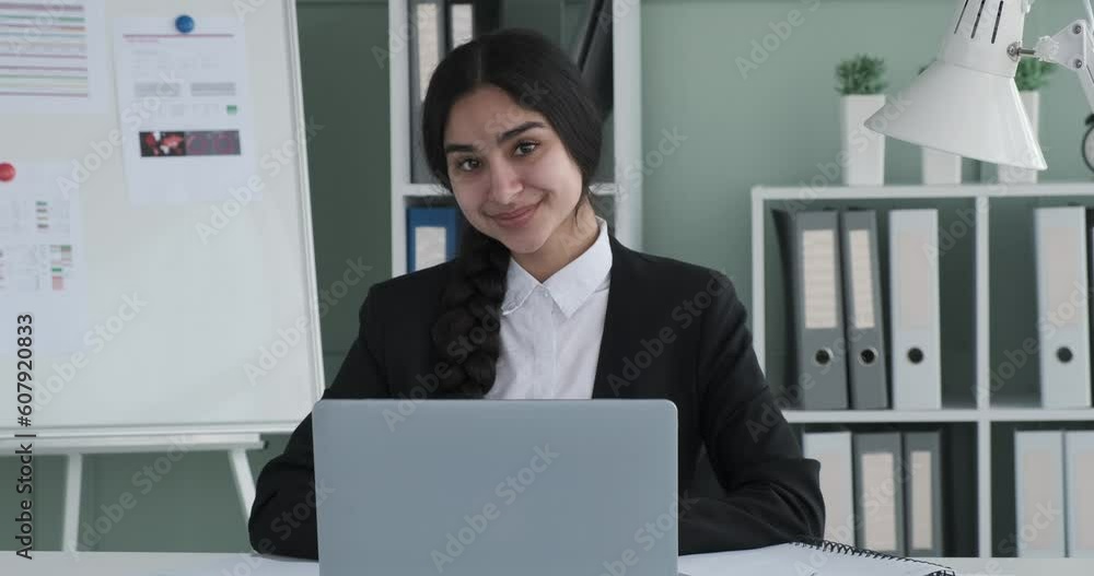 A professional Indian businesswoman sits at her desk in a corporate office, looking directly into the camera with a wide smile that radiates positivity. Her confident demeanor and joyful expression. A professional Indian businesswoman sits at her desk in a corporate office, looking directly into the camera with a wide smile that radiates positivity. Her confident demeanor and joyful expression.
