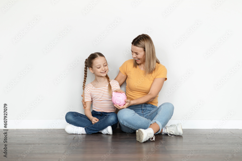 Family Savings. Happy Young Mother And Cute Little Girl Holding Piggy Bank Family Savings. Happy Young Mother And Cute Little Girl Holding Piggy Bank