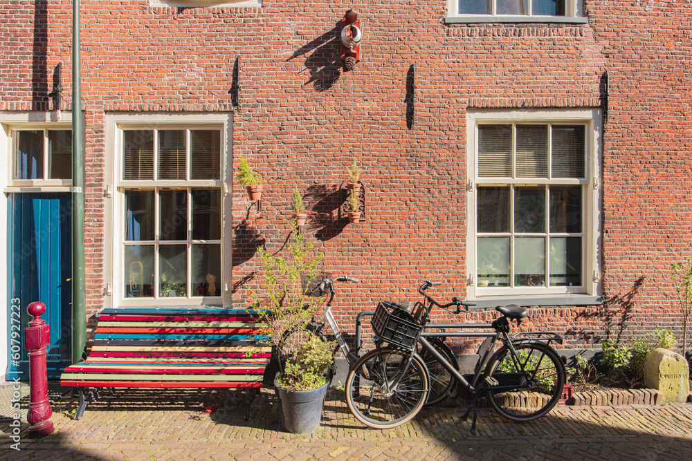 A red brick house wall, with a bench and a bicycle in front of it, in Delft, Netherlands
