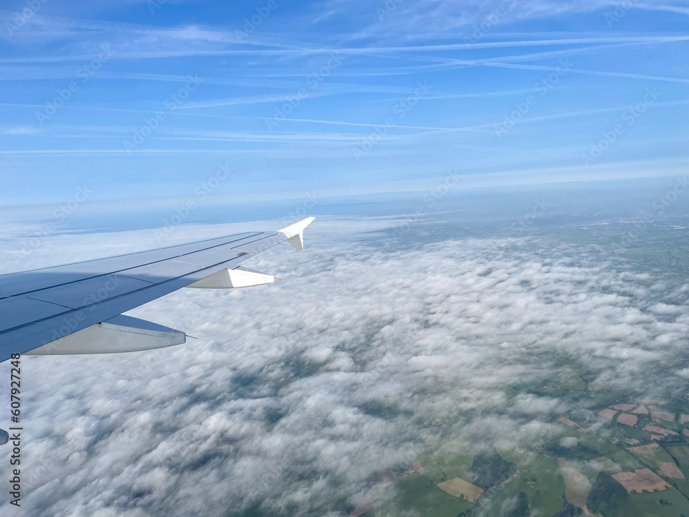 In Flight - Flying and traveling, view from airplane window of the wing with cloudscape and farm countryside below. Travel, Flight, airline, holiday, tourism concept In Flight - Flying and traveling, view from airplane window of the wing with cloudscape and farm countryside below. Travel, Flight, airline, holiday, tourism concept