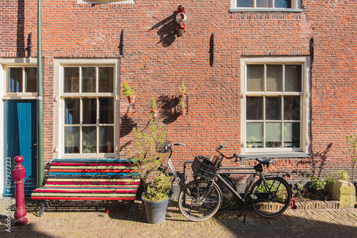 A red brick house wall, with a bench and a bicycle in front of it, in Delft, Netherlands © Belus