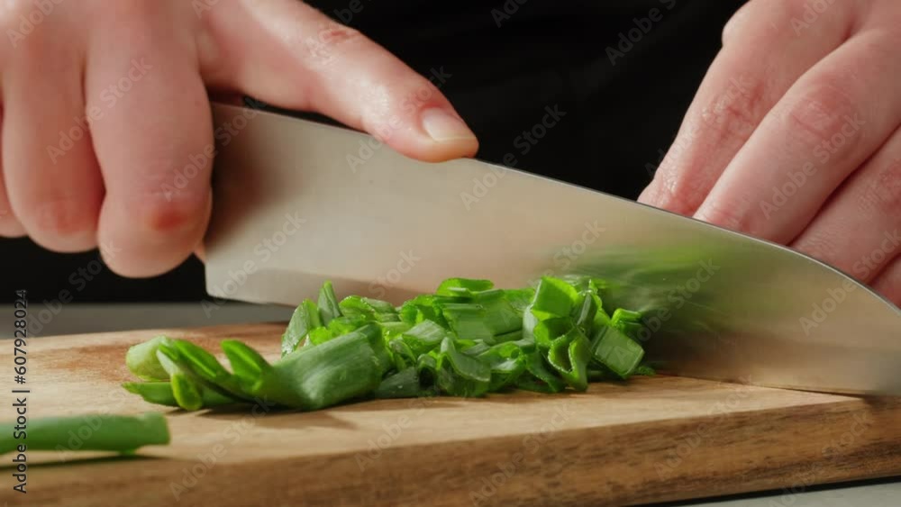 Chef cutting Bunch of green onion feathers by knife on a cutting board on professional restaurant kitchen, Close-up macro rotating shot. Chef cutting Bunch of green onion feathers by knife on a cutting board on professional restaurant kitchen, Close-up macro rotating shot.