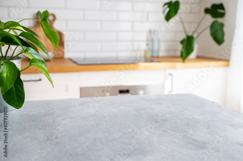 Wooden blue table top with flower pot against blurred white kitchen with cutting board in scandinavian style