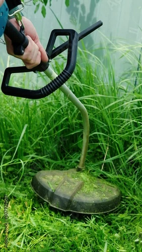 a man mows lawn grass with a lawn mower. petrol lawn mower, trimmer close-up. Man working in the garden