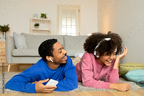 Joyful Black Spouses Listening Music Via Phone Laughing At Home