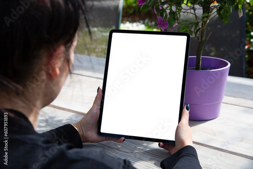 Young woman using Ipad with pencil, blank empty mockup screen. in a field of flowers. Women are drawing in the garden: Freelance, student lifestyle, drawing, gardening.