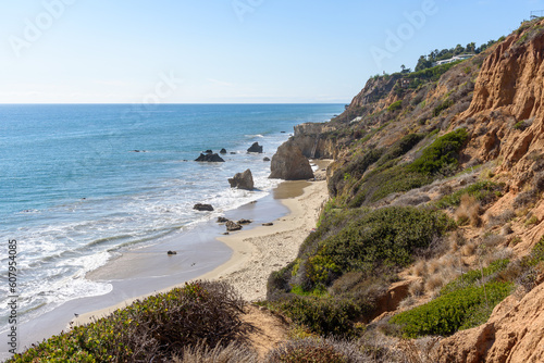 Secluded sandy beach at the foot of a cliff on a sunny autumn day