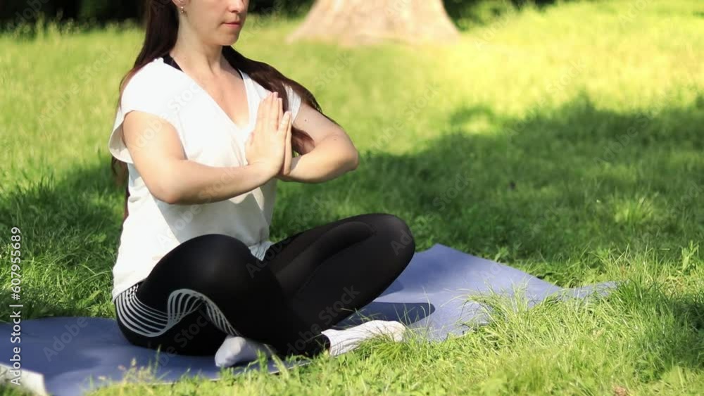 Meditation outdoors in spring or summer. Sports or recreation. A girl sitting in a meditation pose on a yoga mat in the lotus position. Practicing yoga on a sunny day Meditation outdoors in spring or summer. Sports or recreation. A girl sitting in a meditation pose on a yoga mat in the lotus position. Practicing yoga on a sunny day