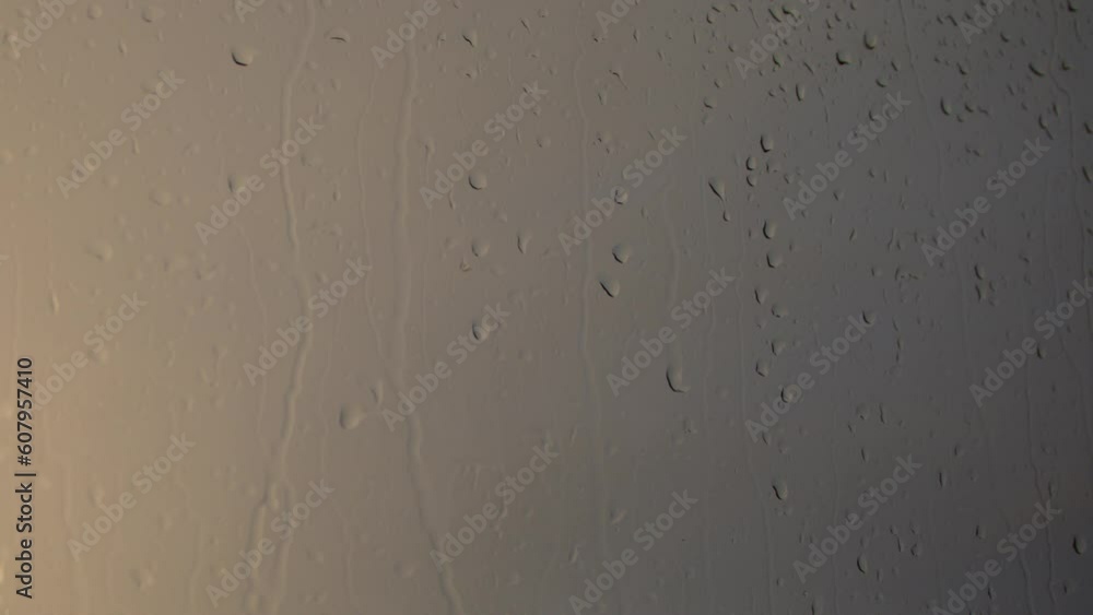 The droplets of water descend leisurely down the wet window, drawing curved lines as they slide through. The droplets of water descend leisurely down the wet window, drawing curved lines as they slide through.