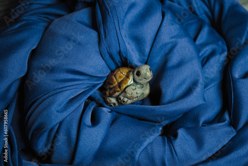Photos Tortuga protegida entre olas de tela azul como símbolo del océano