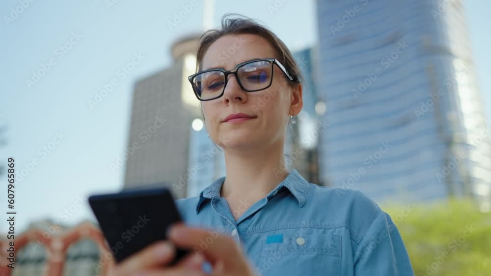 Caucasian woman in glasses walking around the city and using smartphone Caucasian woman in glasses walking around the city and using smartphone