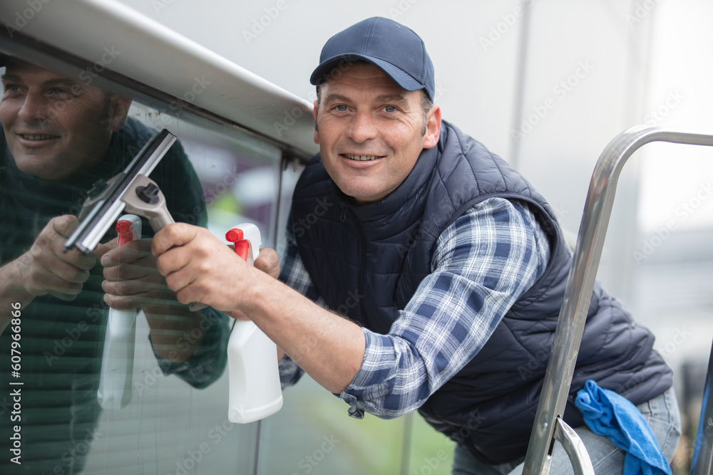 happy man cleaning window in office happy man cleaning window in office