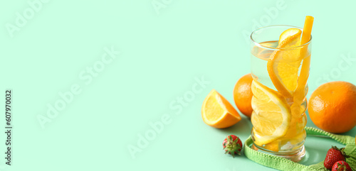 Glass of orange infused water on turquoise background with space for text