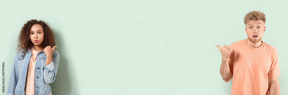 Portrait of confused couple pointing at each other on light background with space for text Portrait of confused couple pointing at each other on light background with space for text