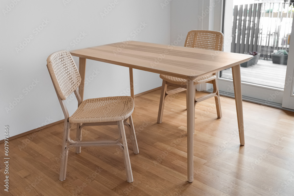 Wooden dining table with wicker chairs in light room Wooden dining table with wicker chairs in light room