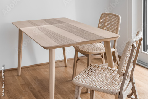 Wooden dining table with wicker chairs in light room