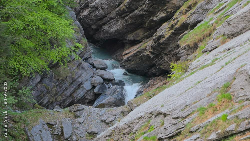 River between rocks of a narrow gorge. Stream of water is squeezed between the sides of the rocks. Linthschlucht, Linth Gorge, Linthal, Canton of Glarus, Switzerland River between rocks of a narrow gorge. Stream of water is squeezed between the sides of the rocks. Linthschlucht, Linth Gorge, Linthal, Canton of Glarus, Switzerland