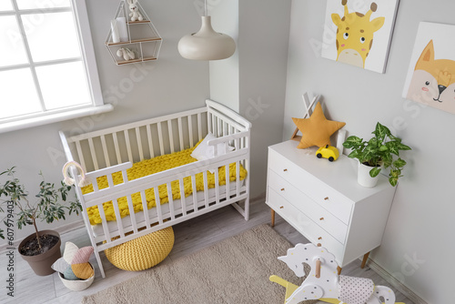 Interior of light bedroom with baby crib, toys and commode © Pixel-Shot