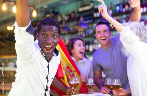 Happy diverse group celebrating Spain at a bar with beer