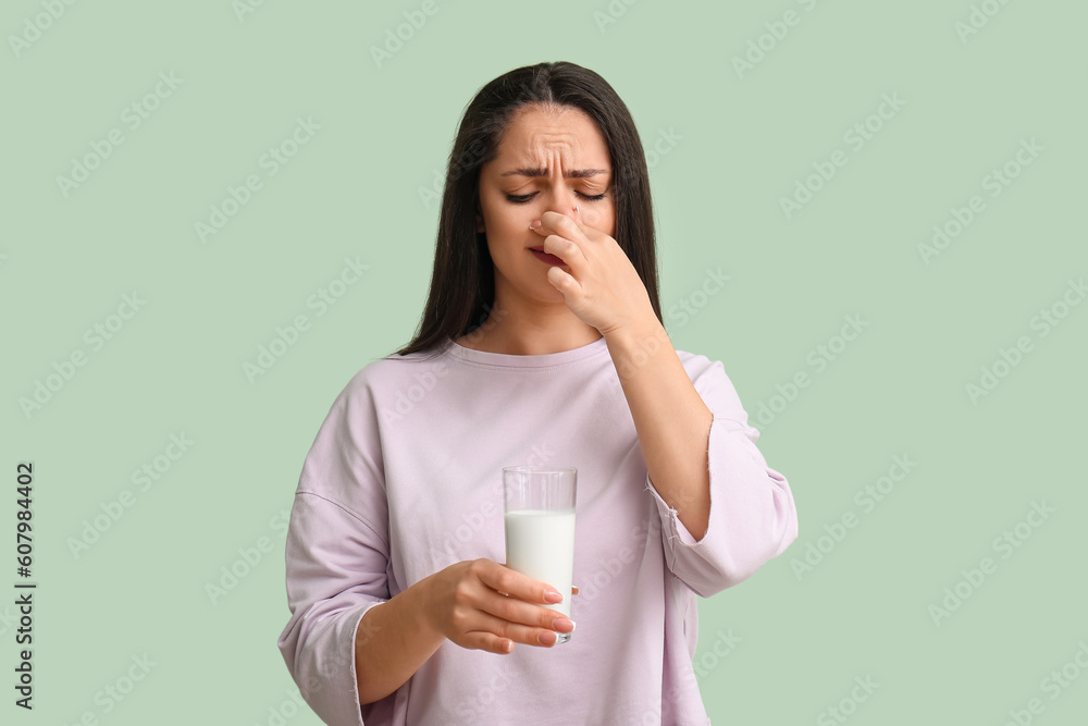Displeased young woman with dairy allergy on mint background Displeased young woman with dairy allergy on mint background