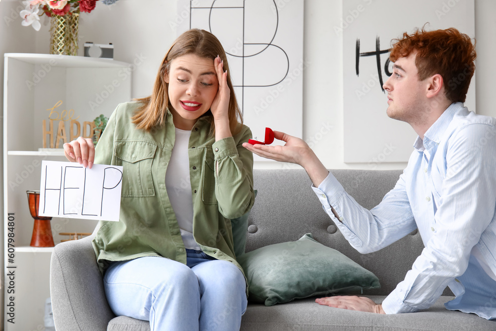 Obraz premium Young woman with word HELP get proposed at home