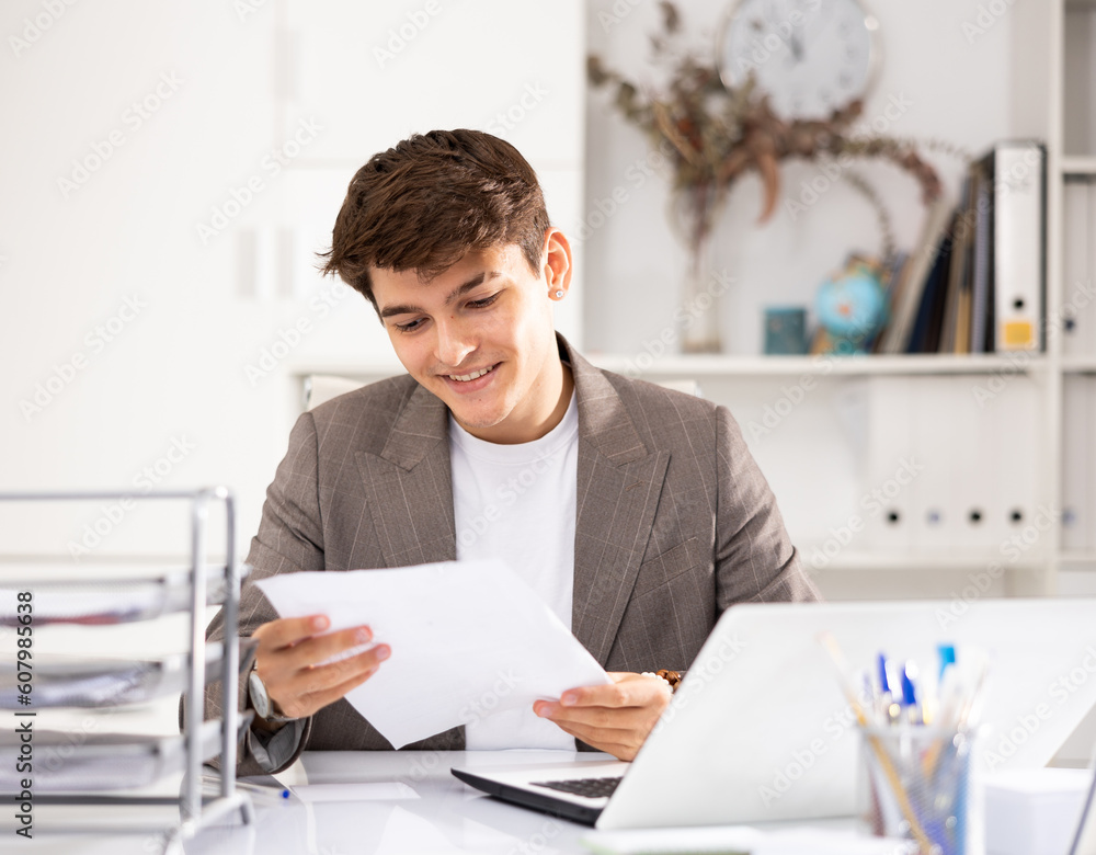 Male bookkeeper doing paperwork in his workplace in office - checks accounting documents