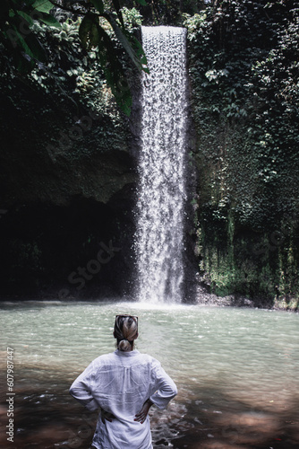 girl facing the tibumana jungle waterfall photo