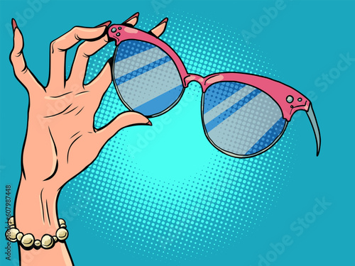 Shop for womens jewelry and glasses. Female hand with manicure holds sunglasses.