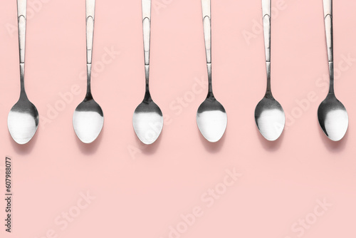 Stainless steel spoons on pink background