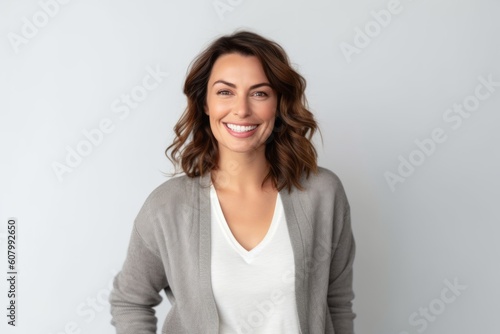 Portrait of beautiful young woman smiling and looking at camera over grey background © Robert MEYNER