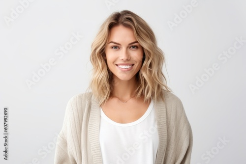 Portrait of beautiful female with blond hair and natural make-up, looking at camera and smiling, standing over white background © Robert MEYNER