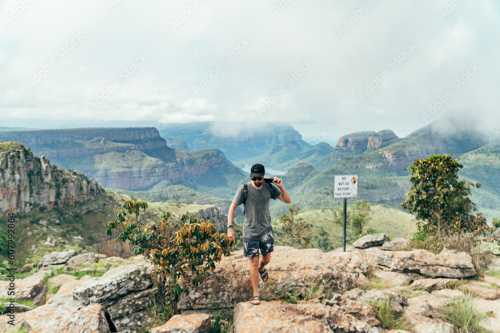 Obraz premium Man on a cliff with a the view from the top of the Blyde river canyon in South Africa.
