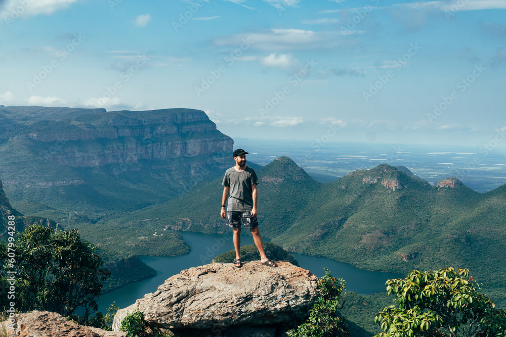 Man on a cliff  looking off into the distance with a the view from the top of the Blyde river canyon in South Africa.