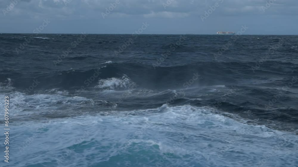 Storm, sea. Wind breaks waves with splashes. Vessel on horizon. White foam on wind. Side view along ship. Storm, sea. Wind breaks waves with splashes. Vessel on horizon. White foam on wind. Side view along ship.