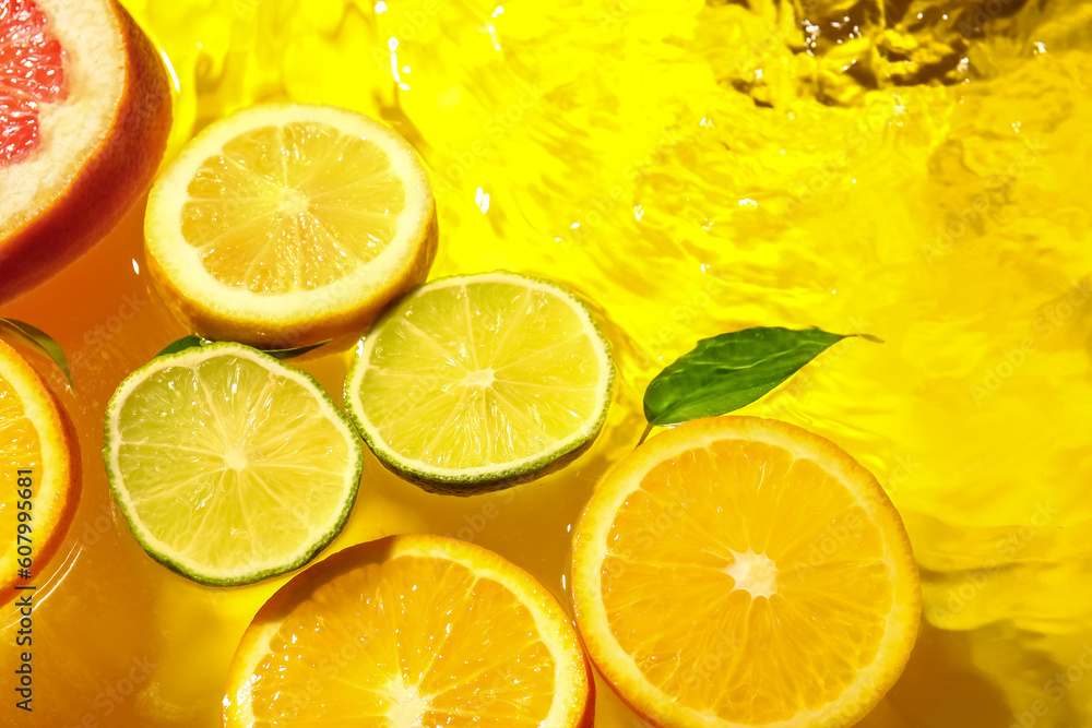 Different citrus fruit slices and leaves in water on yellow background Different citrus fruit slices and leaves in water on yellow background