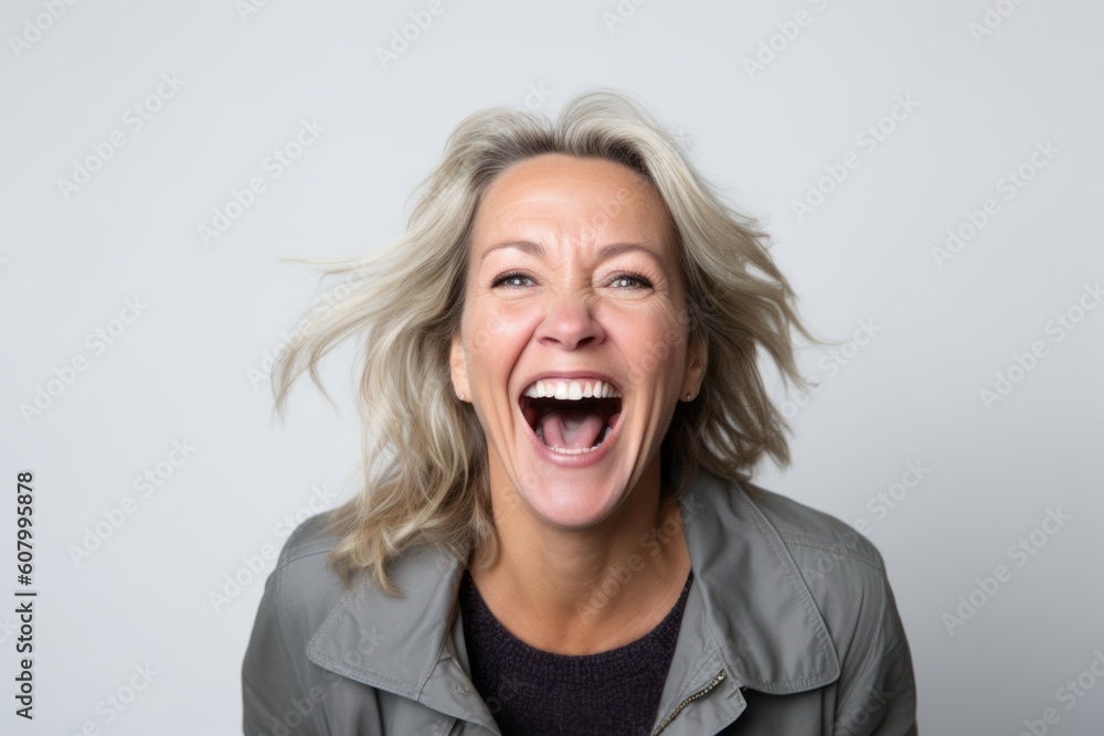 Portrait of a happy woman laughing and looking at camera over gray background Portrait of a happy woman laughing and looking at camera over gray background