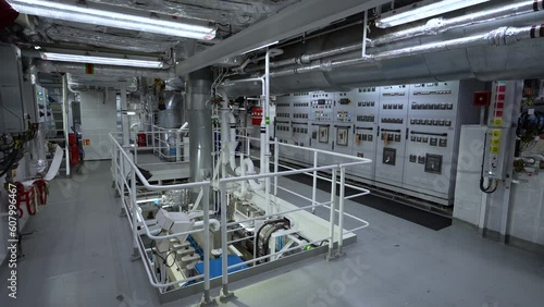 Ship's engine room. Electrical panels. Main engine deck below in opening. Exhaust pipe from engine