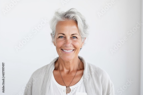 Portrait of a smiling senior woman standing against white wall at home
