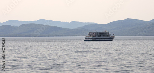 ferry sailing on a lake with mountains in background (boat in water at dusk)