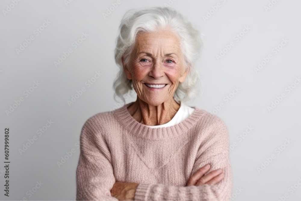 Portrait of happy senior woman with arms crossed looking at camera over grey background Portrait of happy senior woman with arms crossed looking at camera over grey background
