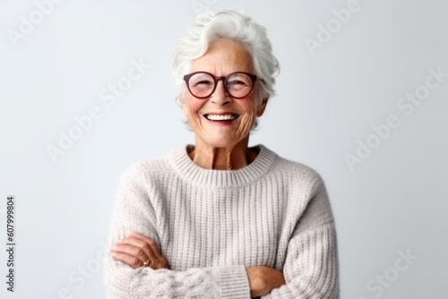 Portrait of a smiling senior woman wearing glasses standing with arms folded isolated over white background