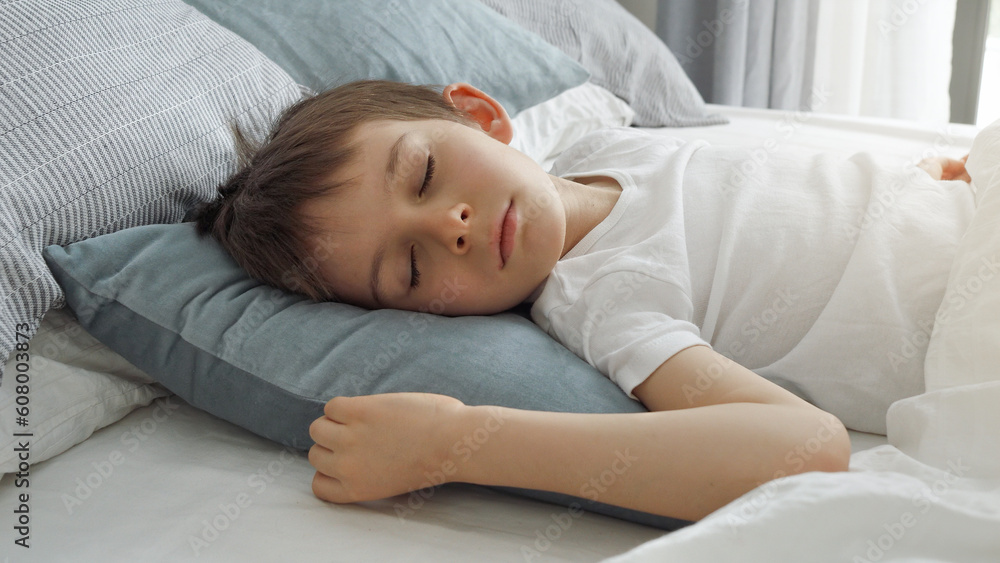 Portrait of little boy sleeping in bed at morning. Modern bedroom with big window. Portrait of little boy sleeping in bed at morning. Modern bedroom with big window.
