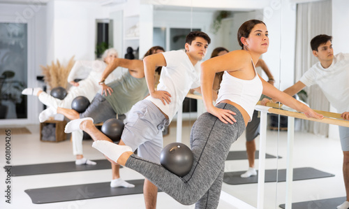 Pilates group workout for a healthy lifestyle. Strong men and women have fun doing sports exercises with ball.