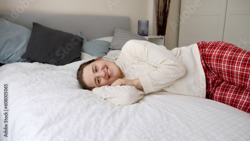 Portrait of happy smiling woman in pajamas lying in bed and enjoying her day